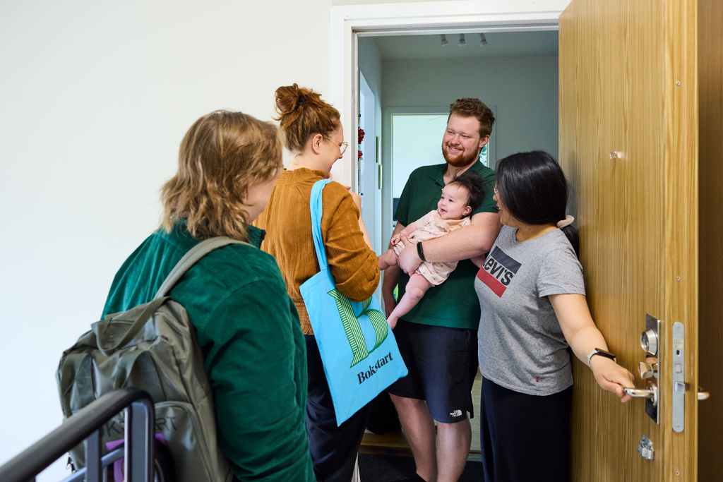 Medarbetare som arbetar med Bokstart möter föräldrar och barn i trappuppgång. 