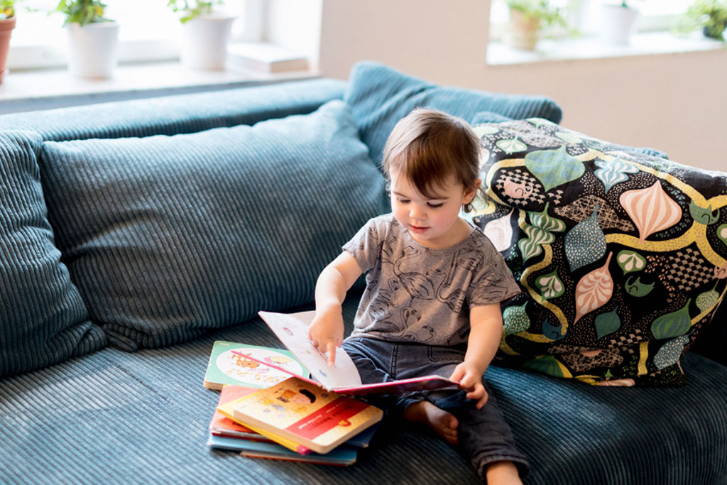 Foto av barn som läser bok i soffa